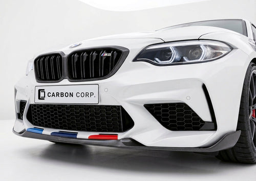 Carbon Corp. BMW M2 F87 front splitter in glossy carbon fibre with M-colour accents on a white car front bumper